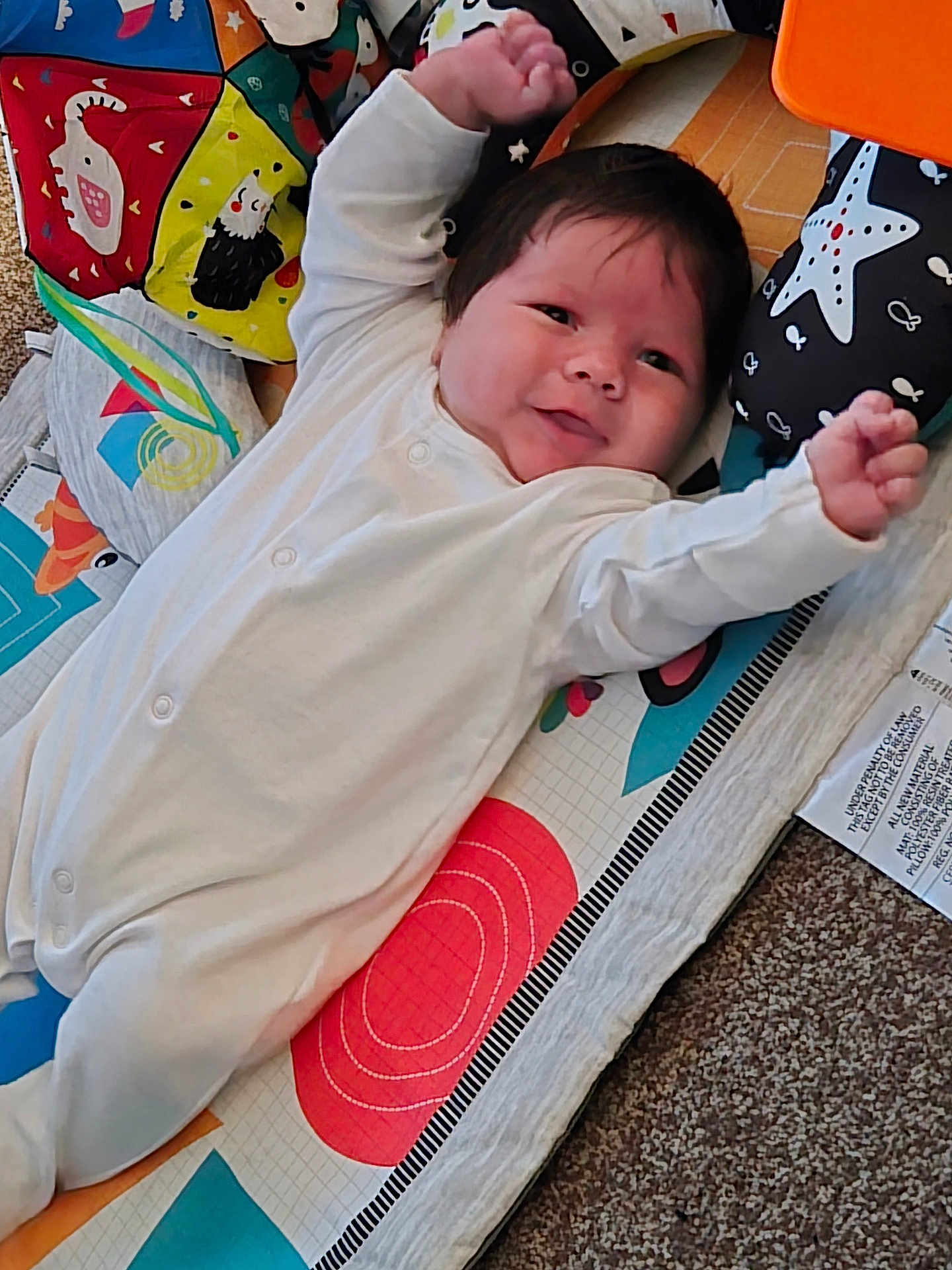 Lucas joined the competition — help win amazing prizes! baby, infant, onesie, play_mat, colorful, smiling, happy, child, indoor, carpet, face, arms_raised, cute, young, person, lying_down, patterned, soft_toys, starfish, animal_prints