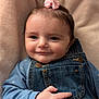 baby, infant, smile, face, denim_overalls, blue_shirt, pink_bow, hand, cute, portrait, child, soft_blanket, indoor, closeup, young_child, adorable, happy, small_hair_tie, skin, cozy