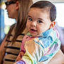 baby, child, woman, person, face, portrait, colorful_clothing, holding, indoor, blurred_background, cute, smiling, happy, casual_wear, watch, glasses, striped_shirt, long_hair, light, soft_focus