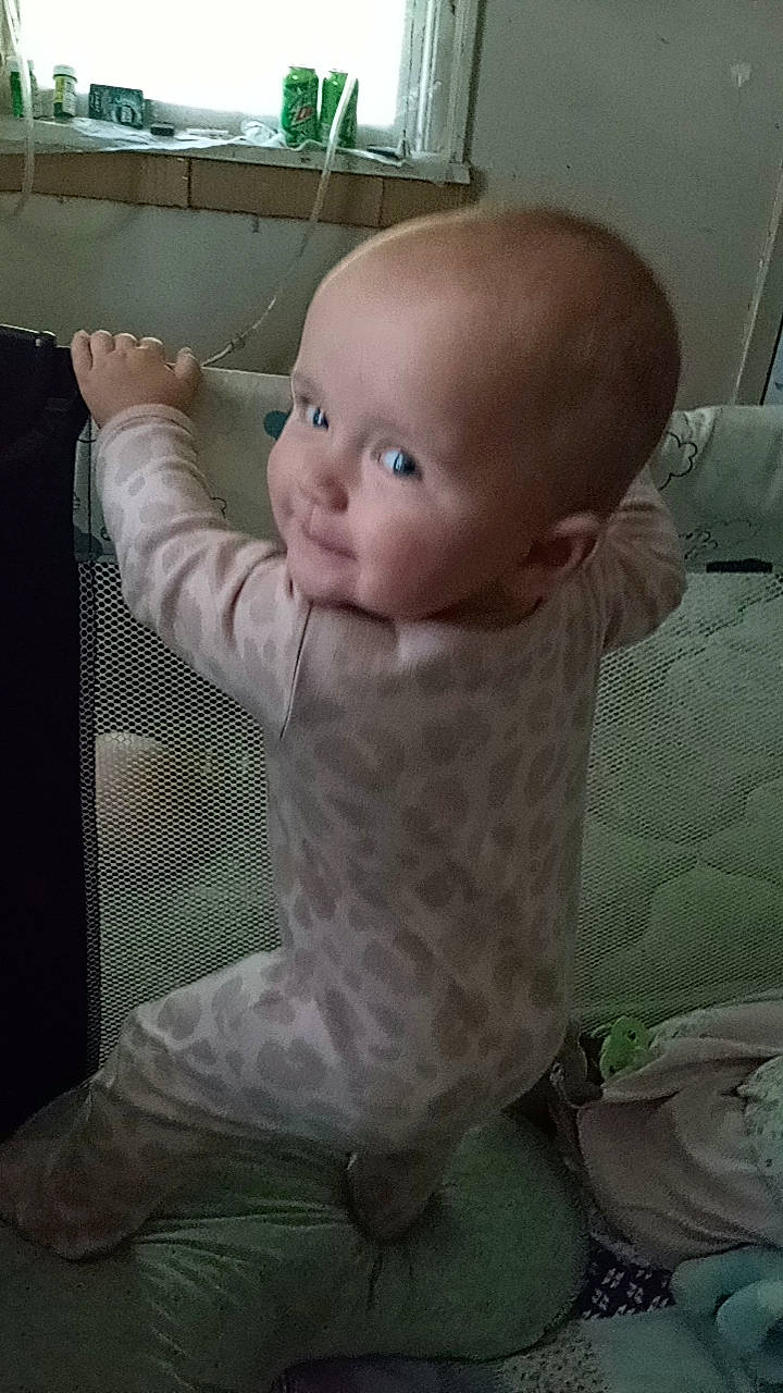 Serenity Ruth is registered to the contest to win money with this photo: baby, baby_products, baby_safety, baby_toddler_clothing, baby_toys, cheek, child, comfort, doll, flooring, gesture, human_body, linens, pattern, person, room, sitting, sleeve, smile, thumb