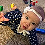 baby, child, polka_dot, headband, flower, carpet, crawling, toy_blocks, indoor, floor, clothing, person, curious, face, hand, footwear, blurred_background, room, playtime, toddler
