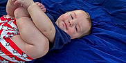 Eastyn is registered to the contest to win money with this photo: baby, blanket, blue_blanket, casual_clothing, child, cute, grass, happy, holding_feet, infant, nature, outdoor, person, playing, red_shorts, relaxed, smiling, stars_pattern, stroller, wheel