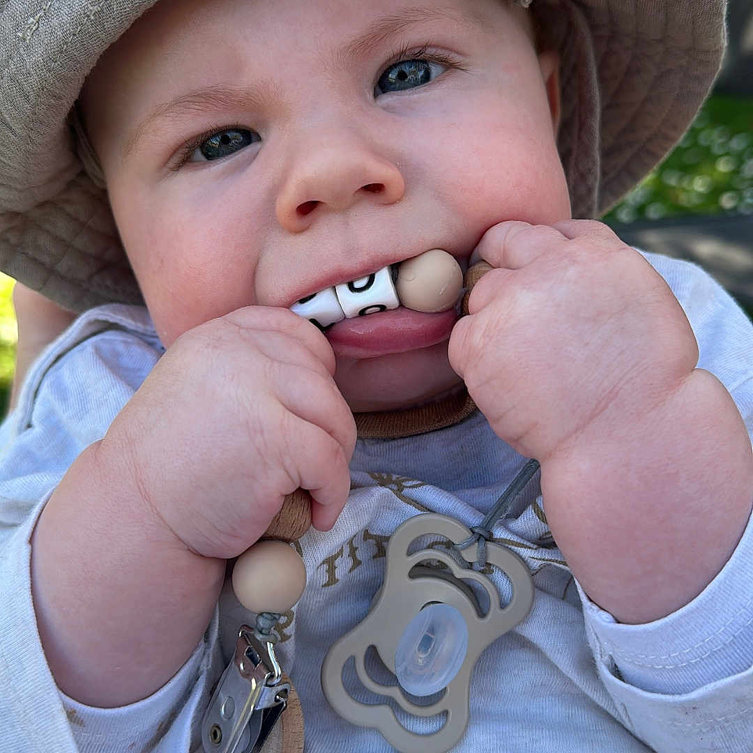Malo a rejoint le concours — aidez-le/la à gagner de superbes lots ! baby, child, hat, pacifier, outdoor, closeup, cute, infant, chewing, hand, clothing, blue_eyes, skin, face, sunlight, toy, accessory, casual, expression, nature