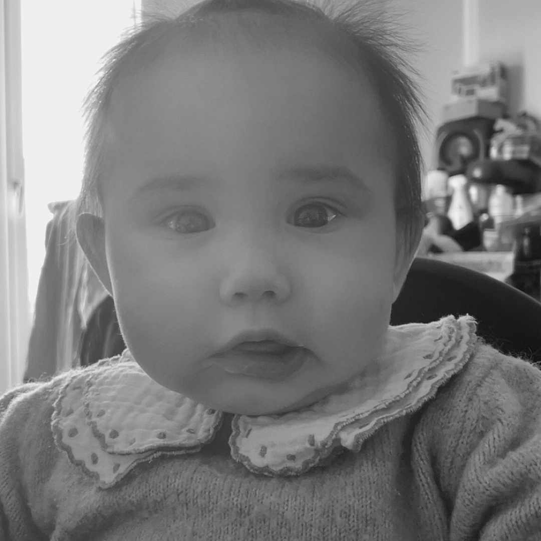 Eloïse a rejoint le concours — aidez-le/la à gagner de superbes lots ! baby, background, black_and_white, child, clothing, collar, curious, expression, face, hair, indoor, infant, person, ponytail, portrait, seat, soft_light, sweater, wide_eyes, window