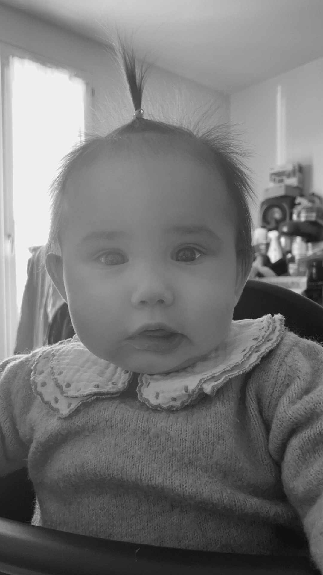 Eloïse a rejoint le concours — aidez-le/la à gagner de superbes lots ! baby, infant, child, ponytail, sweater, collar, face, wide_eyes, indoor, window, curious, portrait, person, clothing, hair, expression, seat, black_and_white, soft_light, background