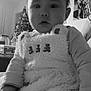 baby, child, face, portrait, indoor, furniture, christmas_tree, holiday, family_photo, clothing, sleeve, hand, soft_texture, black_and_white, cozy, curious, person, young_child, home, decor
