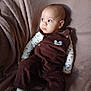 baby, infant, child, overalls, corduroy, blanket, sofa, fabric_texture, looking_away, wide_eyes, portrait, sitting, onesie, patterned_clothing, socks, cozy, soft_lighting, head, cheek, cute