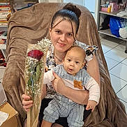 Théo a rejoint le concours — aidez-le/la à gagner de superbes lots ! mother, baby, rose, bouquet, smile, chair, blanket, living_room, bookshelf, books, tiles, floor, portrait, sitting, clothing, socks, gift, home_interior, person, cozy