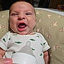 baby, infant, bottle, feeding, onesie, dinosaur_print, cushion, lion_pattern, hand, mouth_open, expression, indoors, closeup, person, child, newborn, sleepwear, cute, human, face