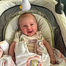 baby, smiling, blanket, rainbow, infant, soft_toy, baby_seat, cushion, happy, child, indoors, portrait, clothing, cute, toddler, comfort, playful, face, person, resting
