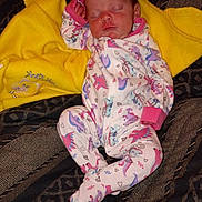 Scarlett is registered to the contest to win money with this photo: newborn, baby, sleeping, infant, child, face, portrait, onesie, dinosaur, pink_clothing, yellow_blanket, couch, blanket, indoor, cozy, peaceful, closed_eyes, lying_down, textile, photography