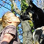 woman, dog, kiss, outdoor, tree, blue_sky, harness, tattoo, sunglasses, pet, nature, animal, portrait, leisure, daylight, closeup, friendship, canine, affection, human