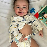 Manuel joined the competition — help win amazing prizes! baby, book, child, closeup, clothing, cute, diaper, face, hand, happy, indoors, infant, lying_down, onesie, pacifier, playful, smiling, toy, white_background, young