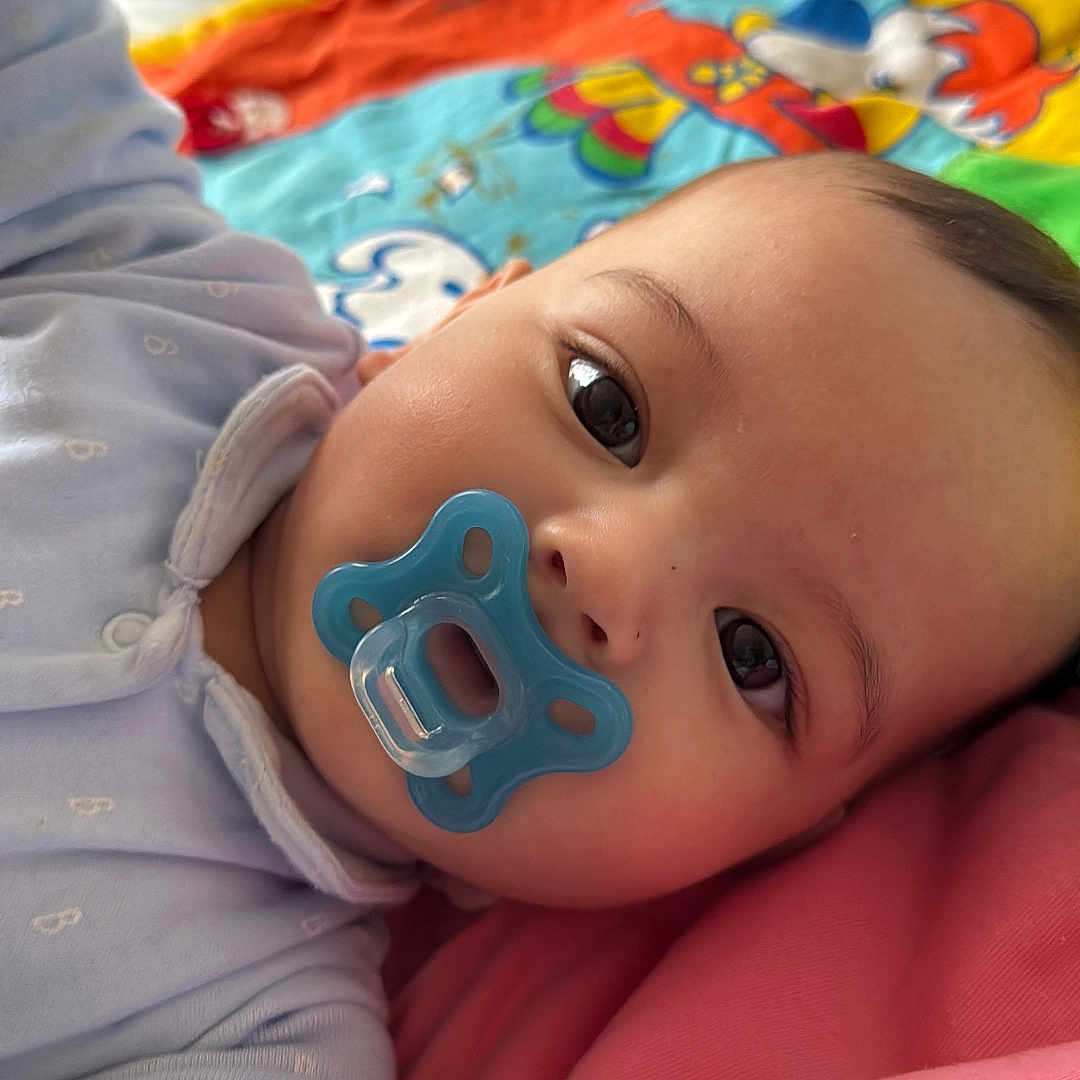 Luca is registered to the contest to win money with this photo: applique, baby, bed, blanket, bodypart, bonnet, cap, clothing, face, finger, furniture, hand, hat, head, newborn, pattern, person, photography, portrait, quilt