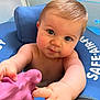 baby, child, blue_eyes, floatation_device, water, toy, pink_toy, arm, hand, face, skin, hair, infant, sitting, closeup, playful, curious, indoors, child_in_water, safe