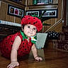 Marcela joined the competition — help win amazing prizes! baby, child, infant, strawberry_costume, fruit_hat, red, green, crawling, portrait, smiling, indoor, living_room, wooden_floor, furniture, cushion, decorations, flowers, plant, polka_dots, costume