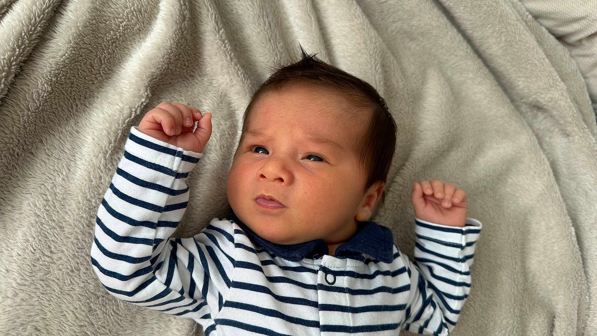 Naïki participe au concours pour gagner de l'argent avec cette photo : baby, infant, striped_clothing, blanket, curious, face, person, newborn, sleepwear, soft_texture, raised_hands, navy_collar, cute, lying_down, indoors, portrait, small_hands, young_child, cozy, expression