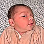 Pierre participe au concours pour gagner de l'argent avec cette photo : baby, newborn, infant, face, skin, clothing, peach_outfit, blanket, pattern, portrait, cute, sleepwear, lying_down, indoor, child, person, soft_light, closeup, young, head