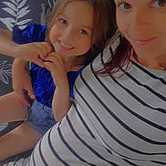 Maëlia participe au concours pour gagner de l'argent avec cette photo : child, woman, smile, heart_hand_gesture, striped_dress, blue_top, happy, portrait, indoor, family, mother_and_daughter, face, person, people, casual, patterned_background, seated, together, love, affection