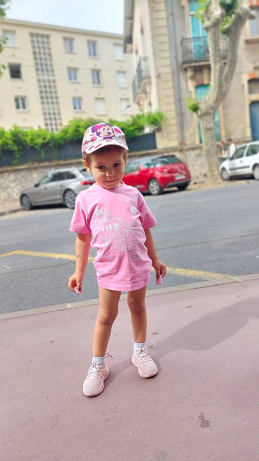 Enxhi Sina a rejoint le concours — aidez-le/la à gagner de superbes lots ! asphalt, building, car, happy, hat, leisure, magenta, pedestrian, person, pink, plant, road, shorts, sidewalk, sleeve, t_shirt, tire, toddler, vehicle, wheel