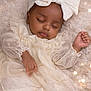 Dior is registered to the contest to win money with this photo: baby, sleeping, dress, headband, bow, blanket, soft_texture, lights, cozy, peaceful, infant, portrait, cute, child, closeup, celebration, indoors, warm, adorable, resting