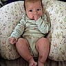 baby, bunny_pattern, child, cozy, curious_eyes, cute, indoor, infant, onesie, person, pillow, plush, portrait, relaxation, resting, sleepwear, small_feet, small_hands, soft_lighting, thumb_sucking
