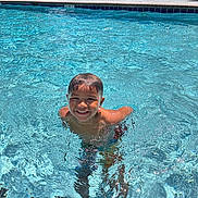 Terrance is registered to the contest to win money with this photo: child, boy, swimming_pool, water, smile, sunlight, outdoor, summer, happy, fun, play, recreation, blue, leisure, person, poolside, sunny, young, vacation, joy