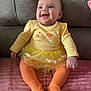baby, child, smiling, toddler, yellow_clothing, orange_tights, tutu, sitting, pink_blanket, couch, happy, cute, indoors, portrait, infant, face, apparel, cozy, soft_texture, funny_outfit