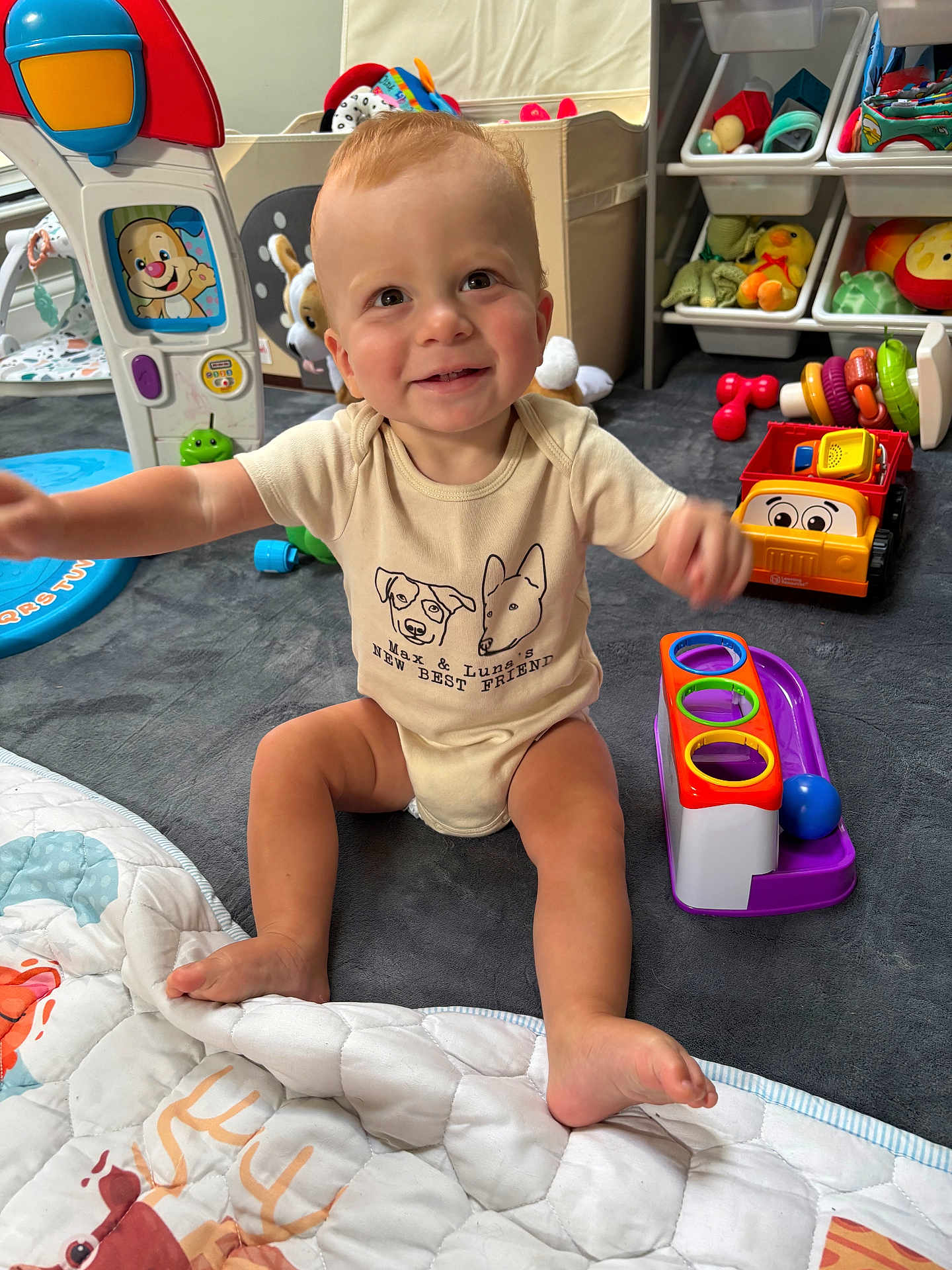 Cooper joined the competition — help win amazing prizes! toddler, child, smiling, indoor, playroom, toys, play_mat, clothing, face, person, colorful, plastic_toys, baby, sitting, happy, floor, cute, reaching, infant, expression
