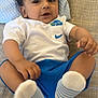 baby, child, infant, cute, lying_down, white_shirt, blue_shorts, socks, bed, pillow, hand, footwear, face, eyes, hair, clothing, indoors, portrait, playful, curious