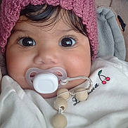 Eloah participe au concours pour gagner de l'argent avec cette photo : baby, pacifier, pink_hat, white_outfit, close_up, face, big_eyes, curly_hair, blanket, beads, cute, infant, child, indoors, soft_texture, warm_clothing, portrait, smiling_eyes, cozy, toddler