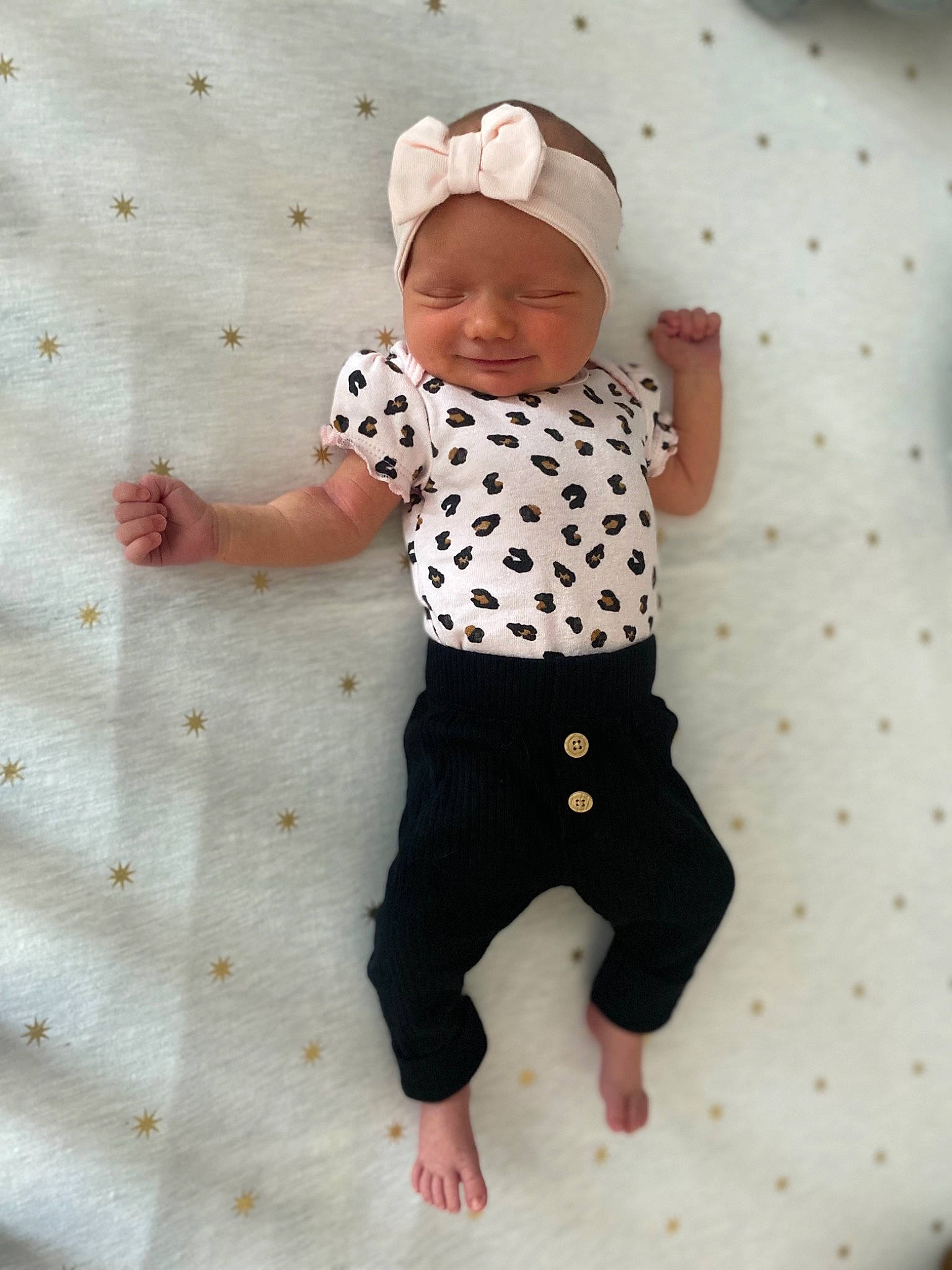 Sloane is registered to the contest to win money with this photo: arm, baby, baby_toddler_clothing, barefoot, cap, child, foot, fun, gesture, happy, headwear, knee, linens, pattern, person, play, skin, sleeve, smile, t_shirt