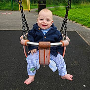 Kas joined the competition — help win amazing prizes! baby, child, swing, playground, outdoor, smiling, happy, park, fence, grass, trees, jacket, clothing, barefoot, metal, chain, seat, pavement, person, infant