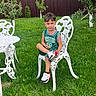 basketball_jersey, boy, casual, child, crossed_legs, cute, daylight, fence, garden, grass, green_jersey, nature, outdoor, portrait, relaxing, sneakers, summer, trees, white_chair, white_table