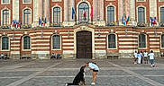 Aion participe au concours pour gagner de l'argent avec cette photo : dog, person, building, architecture, plaza, historic, statue, flag, bench, brick, window, door, street, outdoor, sky, people, interaction, pet, leash, casual