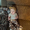 baby, child, smiling, couch, blanket, headband, bow, leopard_print, clothing, pattern, infant, happy, indoor, portrait, sitting, person, cute, fashion, playful, cozy