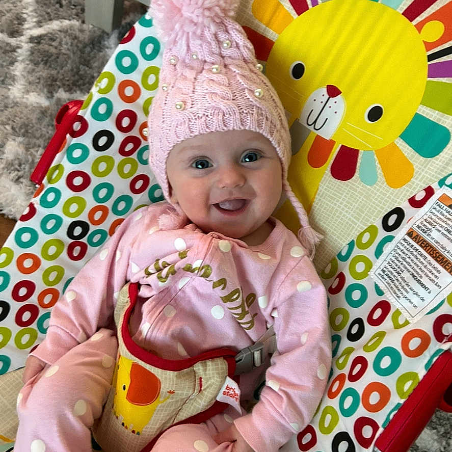 Sylvia is registered to the contest to win money with this photo: baby, baby_bouncer, carpet, child, clothing, colorful, cozy, cute, happy, indoor, infant, lion_design, pink_hat, playtime, polka_dot, portrait, seat, smiling, soft_toys, young_child