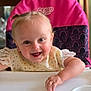 baby, child, high_chair, smiling, happy, polka_dot, bib, face, arm, furniture, indoor, person, hair, table, seat, pink, white, cute, expression, playful