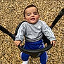 adidas, baby, blue_pants, child, face, fun, gray_sweatshirt, hands, happy, outdoor, person, playground, playtime, seat, smiling, sporty_clothing, swing, toddler, white_socks, wood_chips