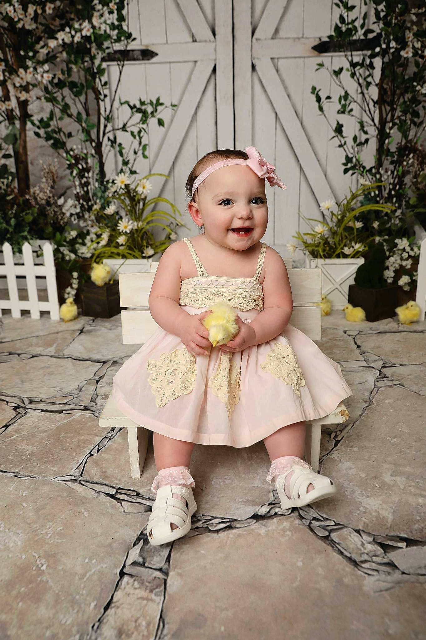 Adeline is registered to the contest to win money with this photo: baby, baby_products, baby_toddler_clothing, child, day_dress, dress, eye, flowerpot, grass, happy, houseplant, human_leg, joy, pattern, person, plant, portrait_photography, sandal, shoe, sitting