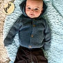 baby, infant, blue_hoodie, black_pants, fluffy_blanket, wooden_plaque, four_months, lying_down, curious_eyes, cozy_clothing, soft_texture, indoor, portrait, cute, child, milestone, knitwear, baby_clothes, blanket, smiling