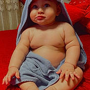 Zain is registered to the contest to win money with this photo: baby, child, towel, blue_towel, red_quilt, cute, indoors, pillow, teddy_bear, face, chubby, sitting, barefoot, curious, soft_lighting, home, portrait, skin, expression, cozy