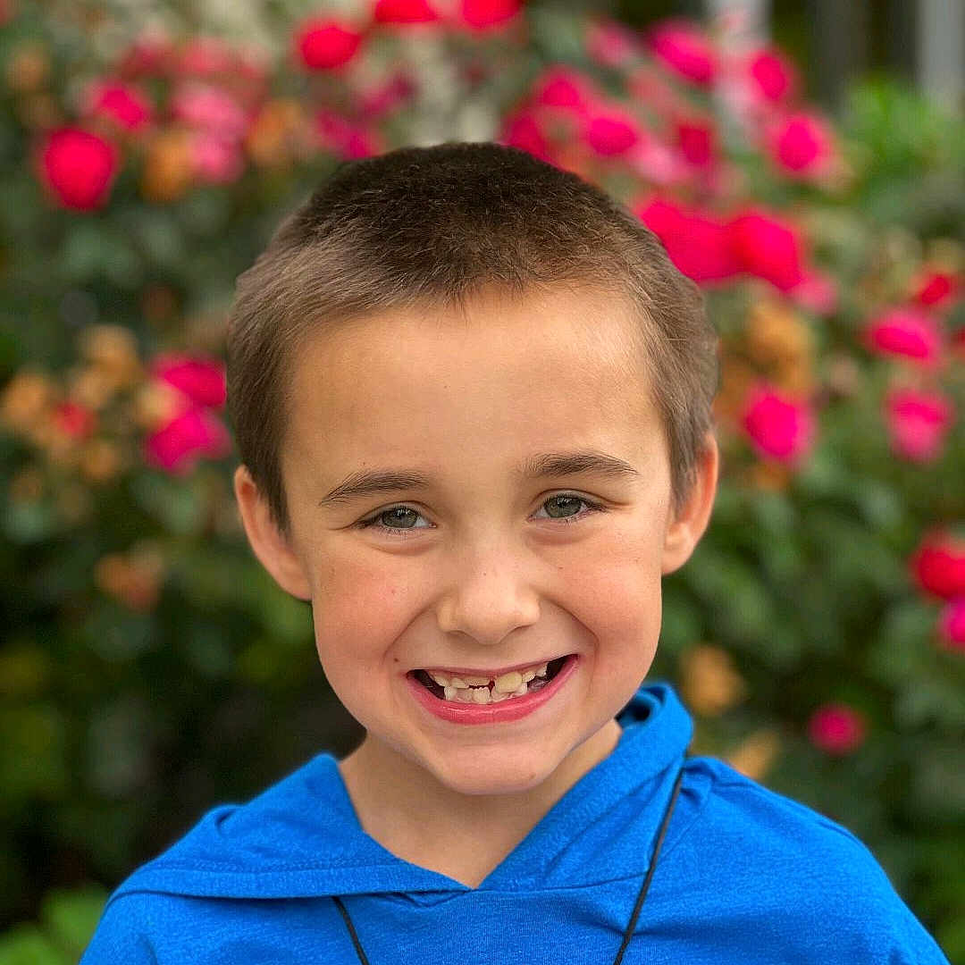 Ryder is registered to the contest to win money with this photo: accessories, boy, child, clothing, face, flower, grass, happy, head, jewelry, male, necklace, person, photography, plant, portrait, pottedplant, purple, smile, t_shirt