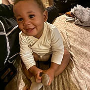 Sintrelle joined the competition — help win amazing prizes! baby, child, smiling, sitting, sock, bed, clothing, curly_hair, happy, indoor, person, cute, playful, toddler, soft_lighting, blanket, cozy, portrait, home, infant