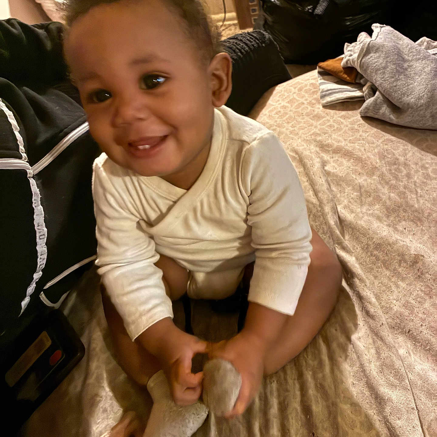 Sintrelle joined the competition — help win amazing prizes! baby, child, smiling, sitting, sock, bed, clothing, curly_hair, happy, indoor, person, cute, playful, toddler, soft_lighting, blanket, cozy, portrait, home, infant