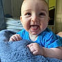 Hayden is registered to the contest to win money with this photo: baby, smiling, blue_shirt, blanket, indoor, face, happy, tongue_out, child, infant, soft_texture, crawling, close_up, cute, person, young_child, skin, hands, expression, cozy