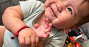 Aziel joined the competition — help win amazing prizes! baby, bracelet, child, close_up, couch, cushion, face, hands, happy, home, indoor, infant, joyful, playroom, portrait, reclining, seated, short_sleeves, smiling, toys