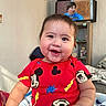 Aziel joined the competition — help win amazing prizes! baby, infant, child, smiling, happy, portrait, indoors, bedroom, red_outfit, mickey_mouse, cartoon, television, blanket, bed, sitting, face, eyes, close_up, home, photography