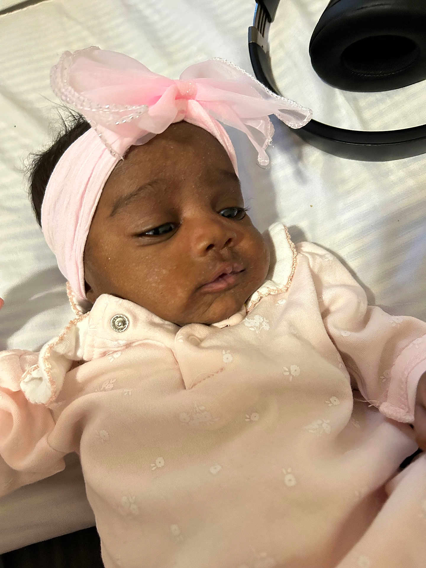 Zolani is registered to the contest to win money with this photo: baby, infant, pink_clothing, headband, bow, face, sleepwear, lying_down, headphones, curious, soft_light, indoor, skin, portrait, young_child, cute, baby_girl, closeup, peaceful, relaxed