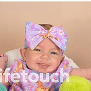 Iris is registered to the contest to win money with this photo: baby, child, headband, bow, smile, portrait, face, clothing, colorful, floral, infant, happy, cute, indoors, person, young, background, soft, photography, watermark